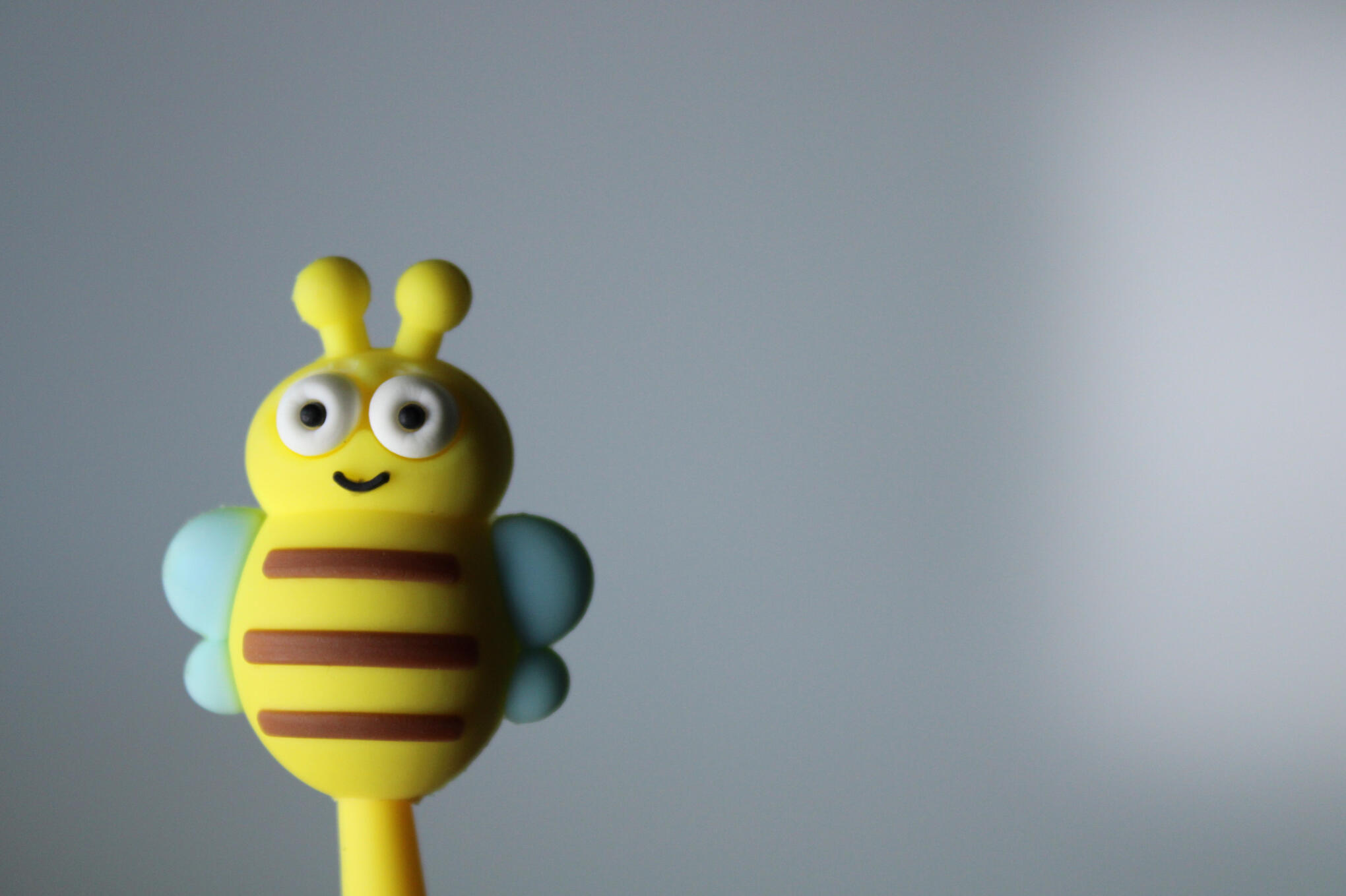 A cute but stupid bee pen on a white background with a dark shadow casted from a bright light.